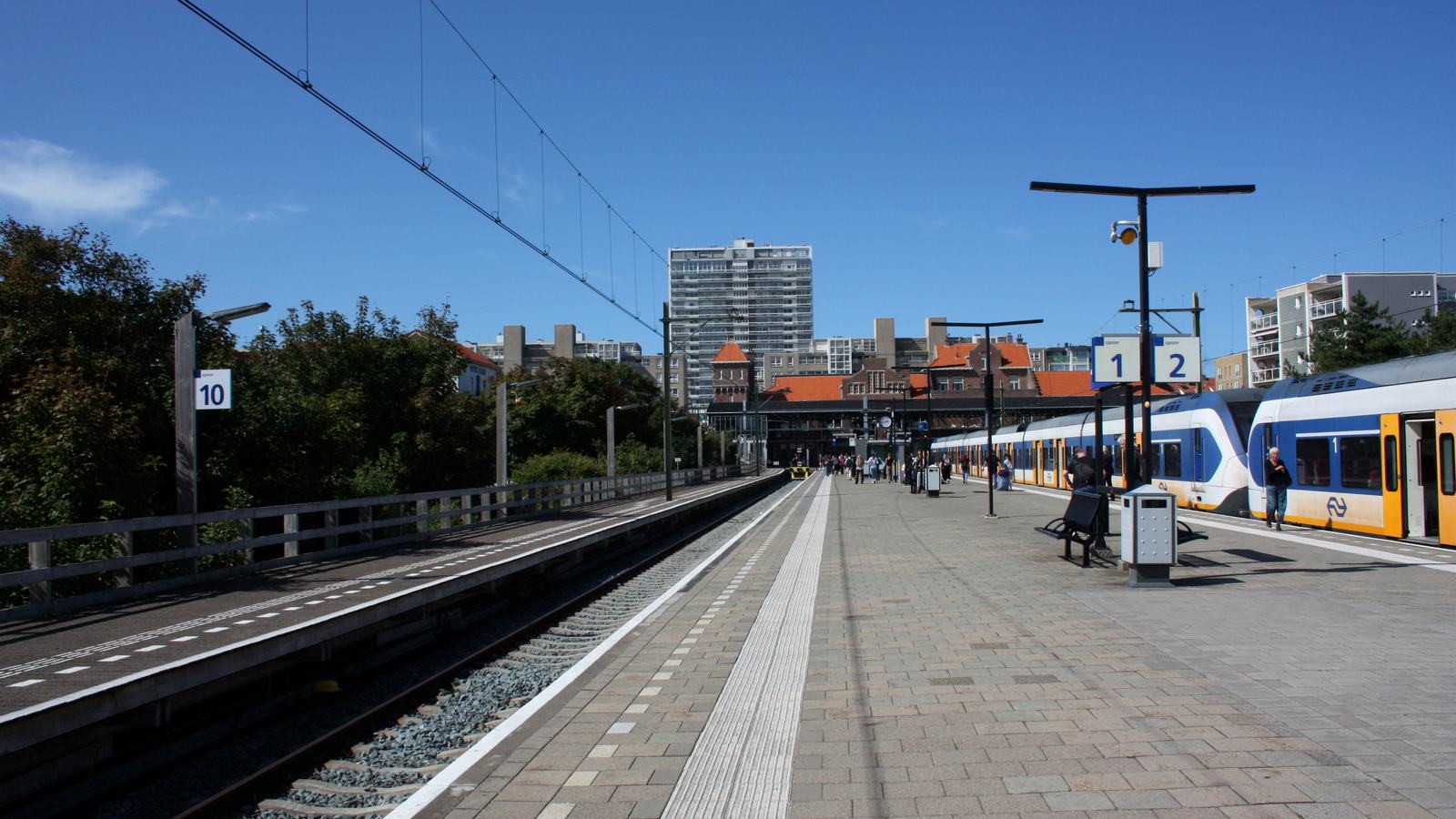 Perron van station Zandvoort aan Zee met een Sprinter van NS langs spoor 2 en het stationsgebouw op de achtergrond